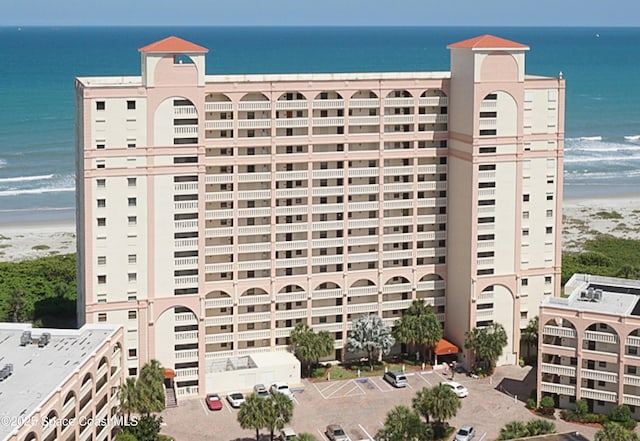 view of building exterior featuring a water view and a beach view