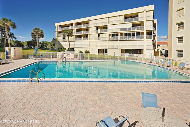 pool with a patio area and fence