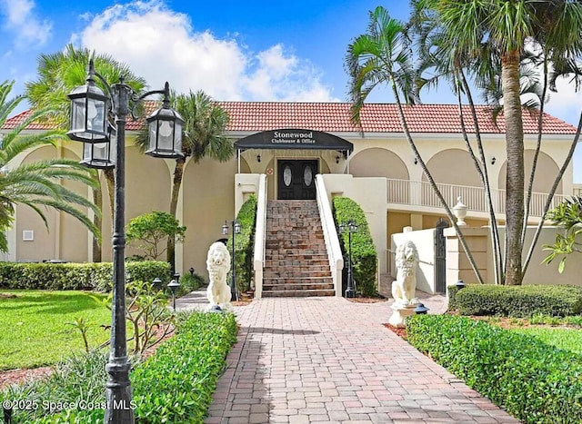 view of front of property with stairs, a tile roof, and stucco siding