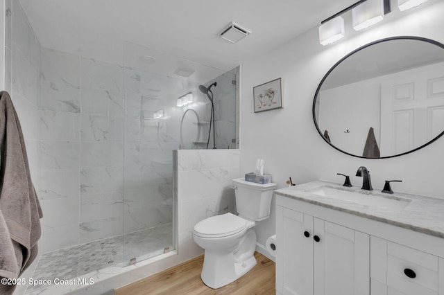 bathroom featuring vanity, wood finished floors, visible vents, a marble finish shower, and toilet