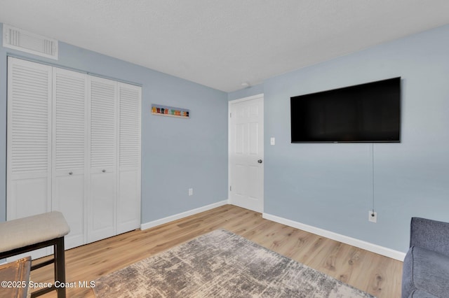 bedroom featuring wood finished floors, visible vents, a closet, and baseboards