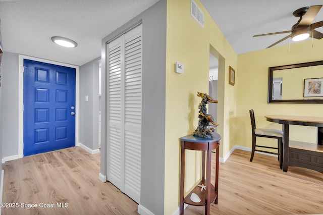 foyer with light wood-style flooring, baseboards, visible vents, and a textured ceiling