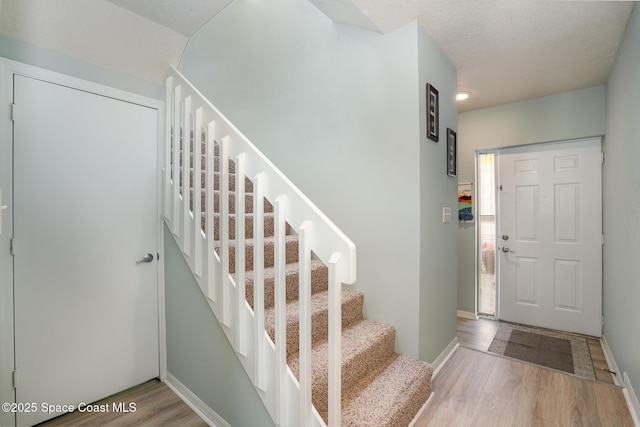 entryway featuring baseboards, stairway, and wood finished floors