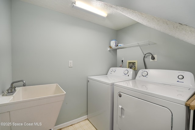 laundry room with light floors, a sink, a textured ceiling, washer and dryer, and laundry area