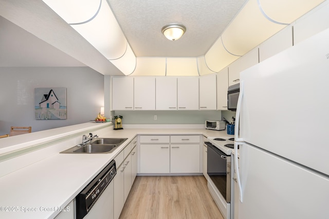 kitchen with light wood finished floors, light countertops, white cabinets, a sink, and white appliances