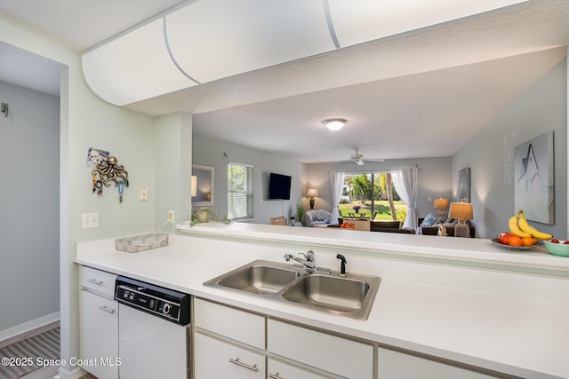 kitchen featuring open floor plan, light countertops, white dishwasher, and a sink