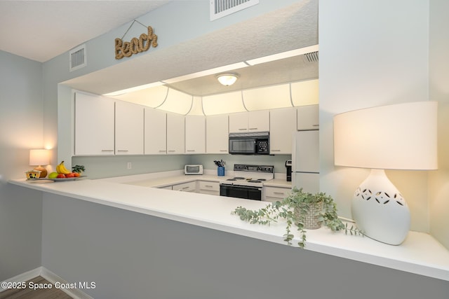 kitchen with a peninsula, white appliances, light countertops, and visible vents