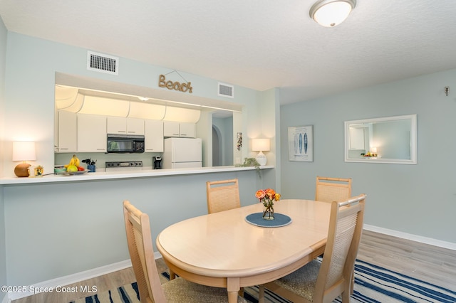 dining room featuring visible vents, baseboards, and wood finished floors