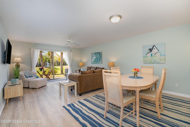 dining room featuring light wood-style floors, baseboards, and a ceiling fan