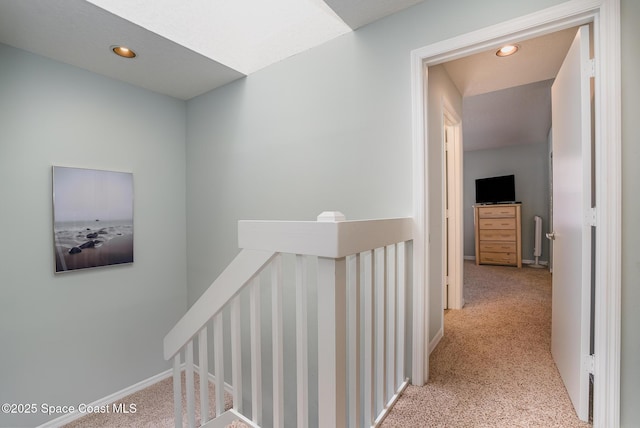 hall with carpet floors, recessed lighting, baseboards, and an upstairs landing