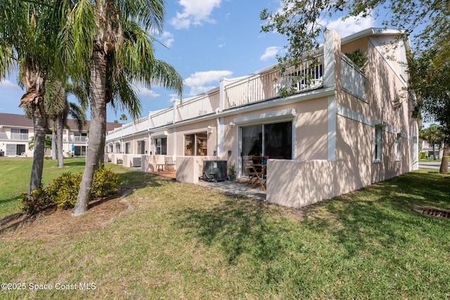 back of house with a yard, a balcony, and stucco siding