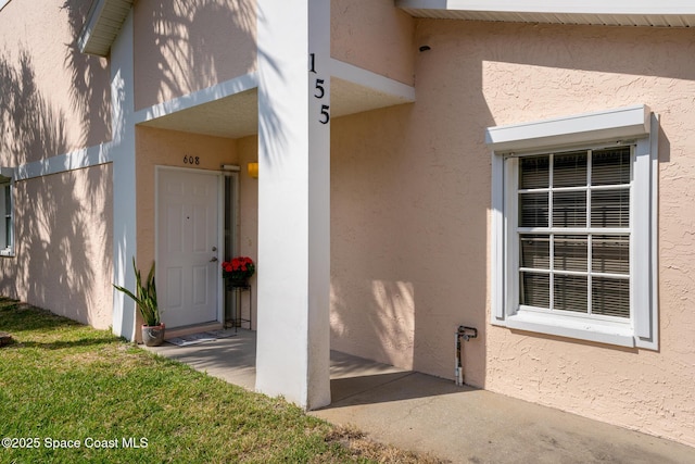 property entrance with a yard and stucco siding