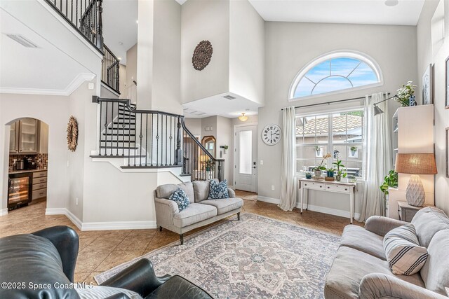living area featuring baseboards, arched walkways, beverage cooler, stairway, and tile patterned flooring