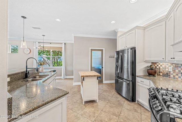 kitchen featuring ornamental molding, a sink, stainless steel fridge, gas range oven, and backsplash