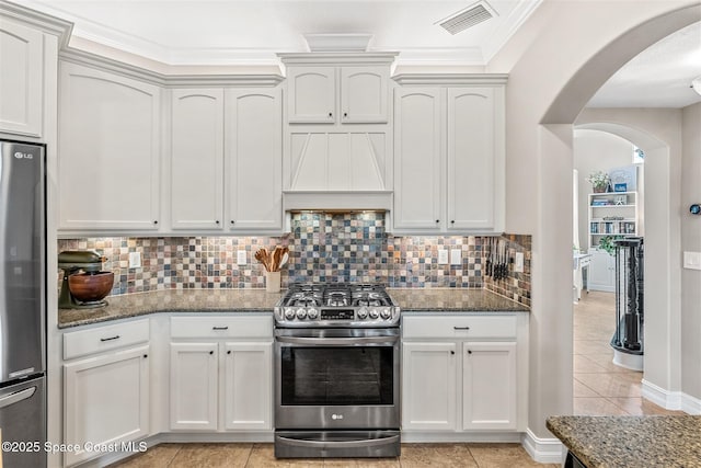 kitchen featuring arched walkways, dark stone counters, visible vents, and stainless steel appliances