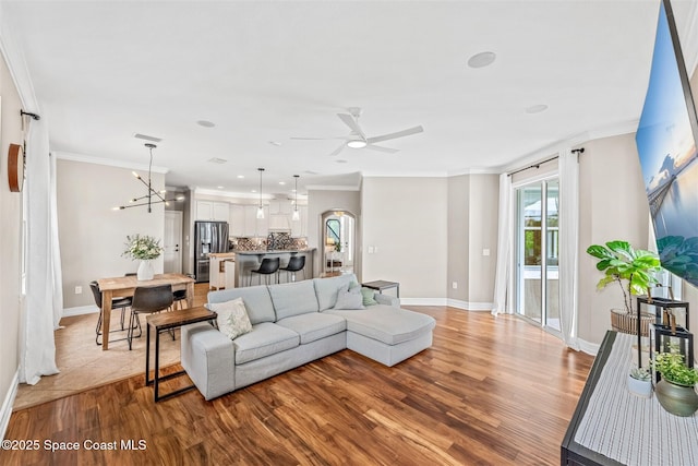 living room with a ceiling fan, wood finished floors, and ornamental molding