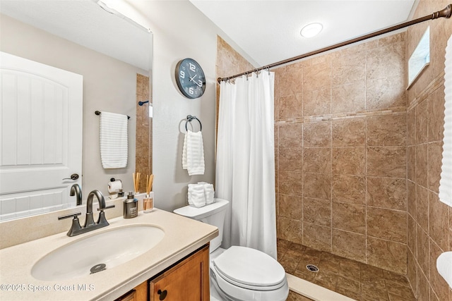 full bath with tiled shower, vanity, and toilet