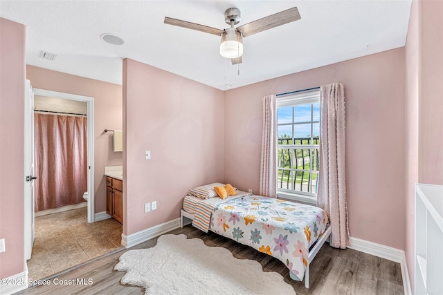 bedroom featuring visible vents, baseboards, ceiling fan, light wood finished floors, and connected bathroom