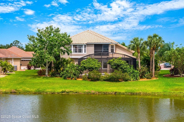 back of property with a water view, a tile roof, and stucco siding