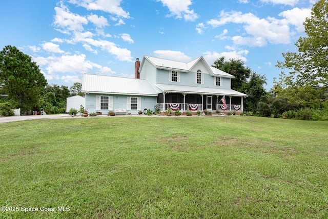 farmhouse-style home with covered porch, metal roof, a chimney, and a front lawn