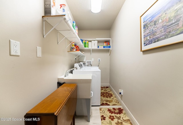 clothes washing area with laundry area, washing machine and dryer, and baseboards