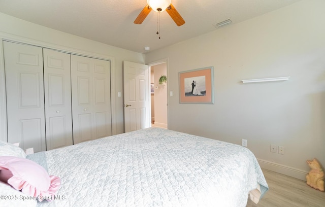 bedroom with a ceiling fan, visible vents, baseboards, a closet, and light wood finished floors