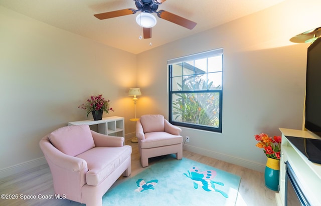 sitting room featuring a ceiling fan, baseboards, and wood finished floors