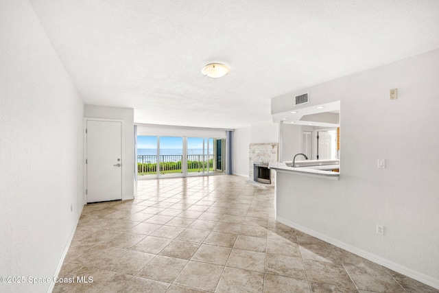 unfurnished living room featuring light tile patterned floors, baseboards, a fireplace, and visible vents