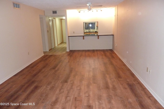 spare room with baseboards, visible vents, a sink, and wood finished floors