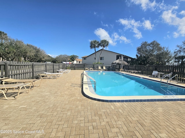 community pool with a patio area and fence