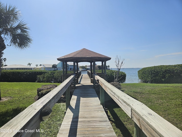 dock area with a water view, a lawn, and a gazebo