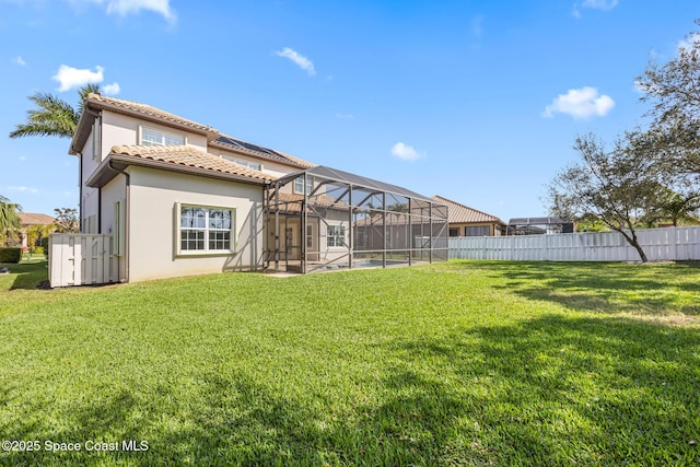 rear view of property featuring glass enclosure, a tile roof, fence, and stucco siding