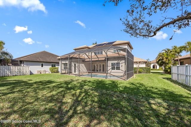 rear view of house with a lanai, fence, a tiled roof, a lawn, and a fenced in pool