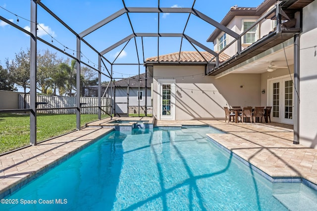 view of swimming pool with ceiling fan, a lanai, fence, french doors, and a patio area