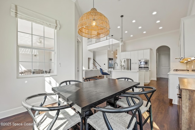 dining room featuring baseboards, arched walkways, dark wood-type flooring, crown molding, and recessed lighting