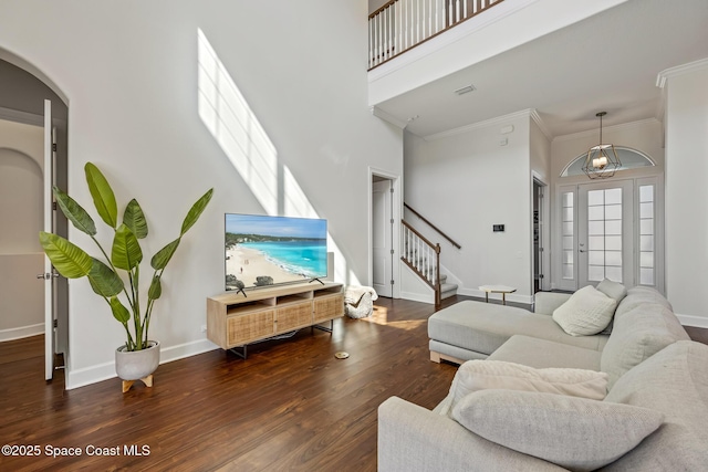 living room with baseboards, a towering ceiling, stairway, wood finished floors, and crown molding