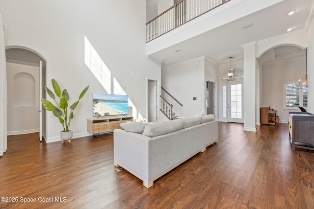 living area featuring a towering ceiling, baseboards, dark wood finished floors, and ornamental molding