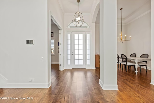 foyer entrance with an inviting chandelier, crown molding, baseboards, and wood finished floors