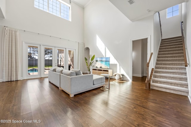 living area featuring a high ceiling, visible vents, stairs, french doors, and dark wood-style floors