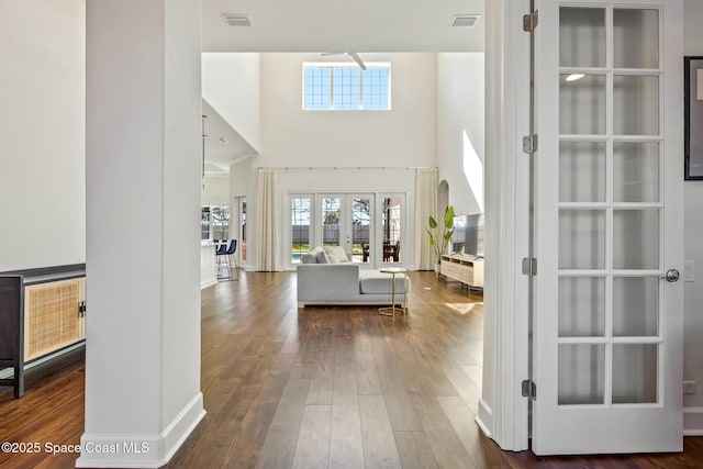 foyer entrance with a towering ceiling, dark wood-style floors, visible vents, and french doors