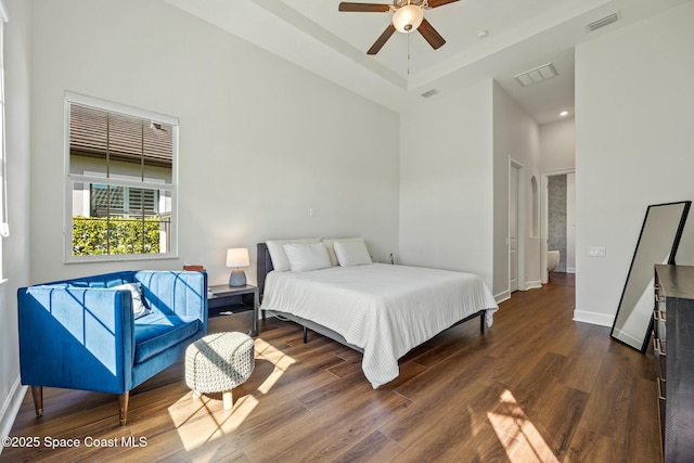 bedroom with baseboards, visible vents, and wood finished floors