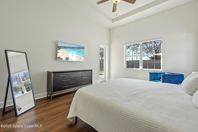 bedroom with multiple windows, baseboards, a raised ceiling, and dark wood-style flooring