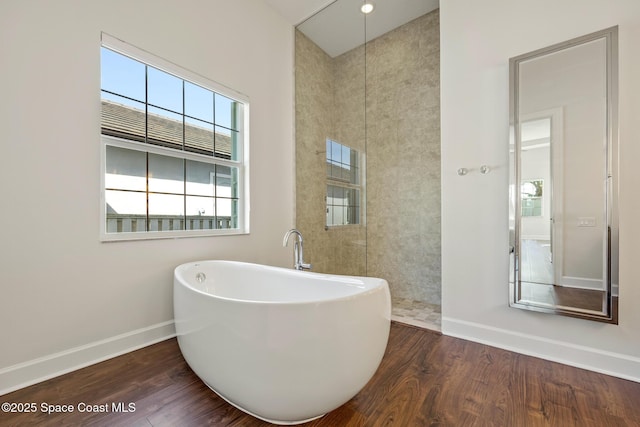 bathroom with a freestanding tub, baseboards, and wood finished floors