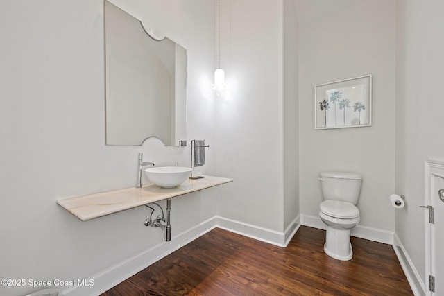 bathroom featuring toilet, baseboards, a sink, and wood finished floors