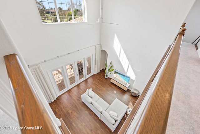 living room with ceiling fan, a high ceiling, arched walkways, and wood finished floors