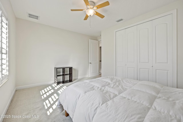 carpeted bedroom featuring ceiling fan, a closet, visible vents, and baseboards