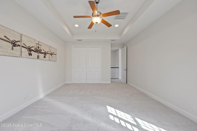 unfurnished bedroom featuring baseboards, visible vents, a raised ceiling, and recessed lighting