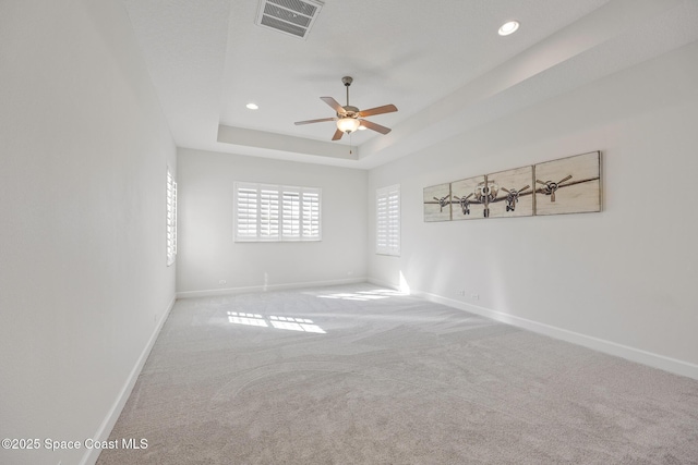 spare room with recessed lighting, a raised ceiling, visible vents, carpet flooring, and baseboards