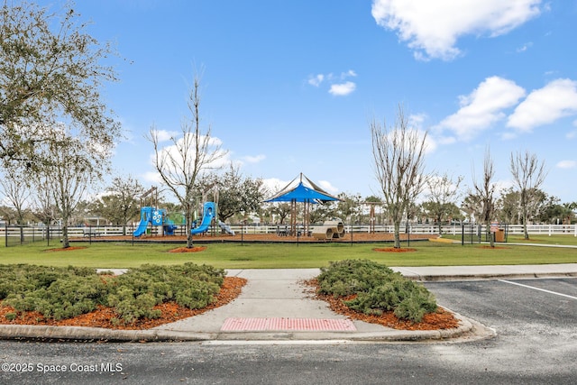 view of community with playground community, fence, and a lawn