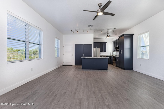 kitchen featuring appliances with stainless steel finishes, open floor plan, a kitchen island, wood finished floors, and baseboards